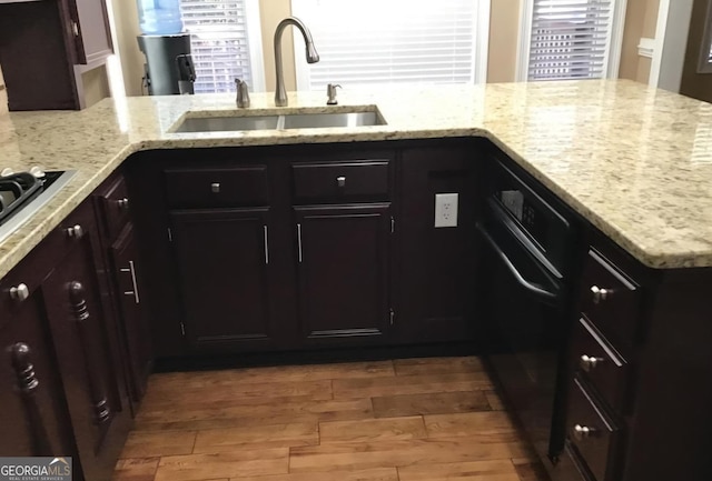 kitchen with kitchen peninsula, light stone countertops, sink, and wood-type flooring