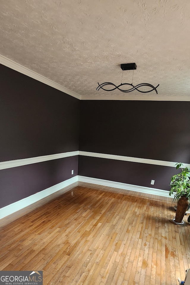 empty room with crown molding, wood-type flooring, and a textured ceiling