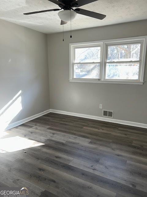 empty room with dark hardwood / wood-style floors, ceiling fan, and a textured ceiling