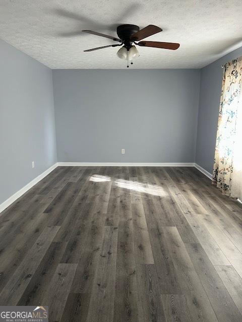 empty room with a textured ceiling, dark hardwood / wood-style floors, and ceiling fan