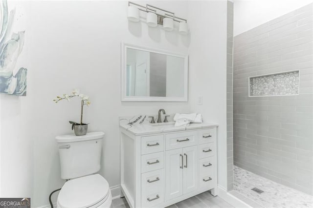 bathroom featuring tiled shower, vanity, and toilet