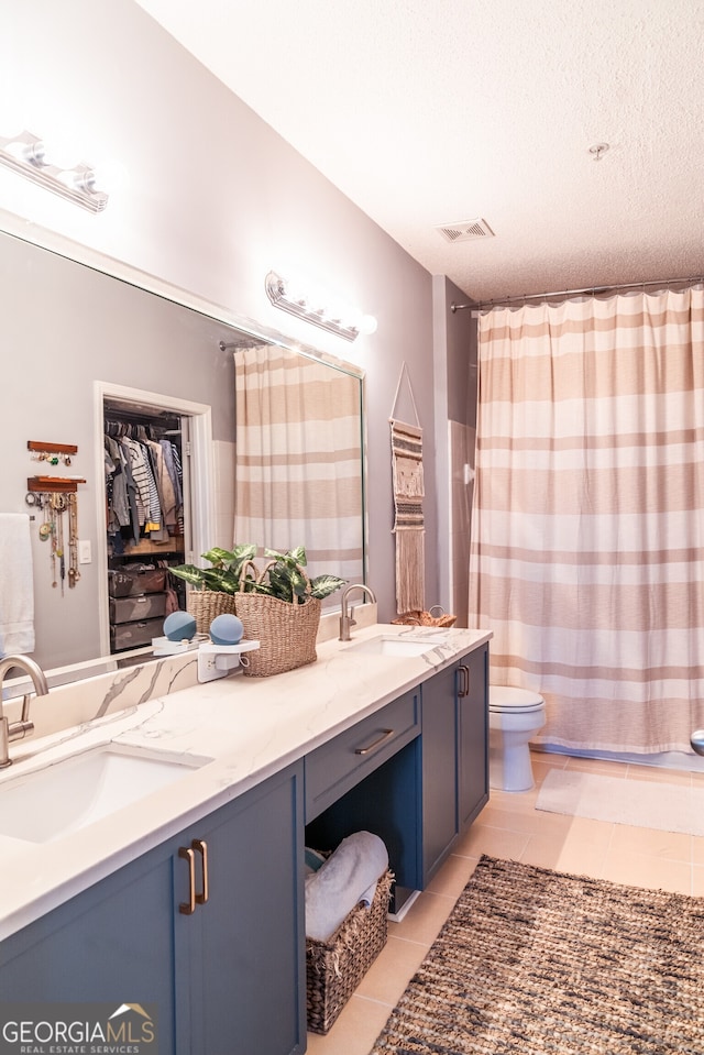 bathroom with toilet, a textured ceiling, vanity, and tile patterned floors