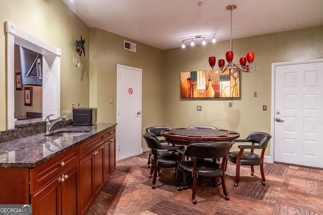 dining room with parquet floors, sink, and track lighting