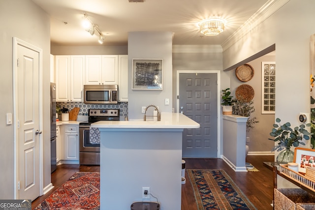 kitchen featuring white cabinets, ornamental molding, appliances with stainless steel finishes, tasteful backsplash, and a kitchen island