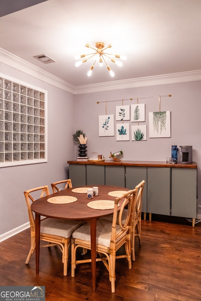 dining room with dark wood-type flooring, an inviting chandelier, and ornamental molding