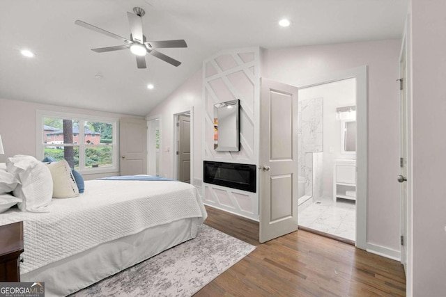 bedroom featuring ceiling fan, dark hardwood / wood-style floors, lofted ceiling, and connected bathroom