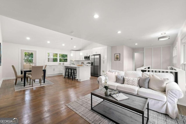 living room with dark hardwood / wood-style flooring, sink, and vaulted ceiling