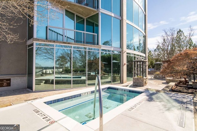 rear view of house with a balcony and a hot tub