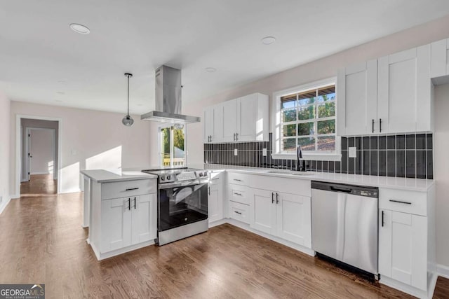 kitchen featuring island range hood, white cabinetry, sink, and appliances with stainless steel finishes