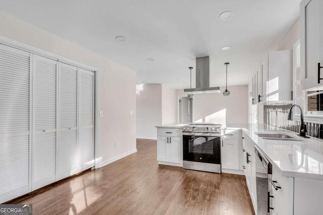 kitchen featuring stainless steel appliances, sink, exhaust hood, decorative light fixtures, and white cabinets