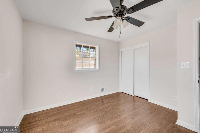 unfurnished bedroom with ceiling fan, a closet, and hardwood / wood-style flooring