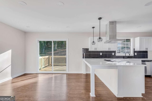 kitchen featuring stainless steel dishwasher, a wealth of natural light, decorative light fixtures, white cabinetry, and island exhaust hood