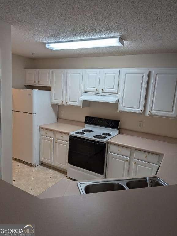 kitchen featuring a textured ceiling, white appliances, white cabinetry, and sink