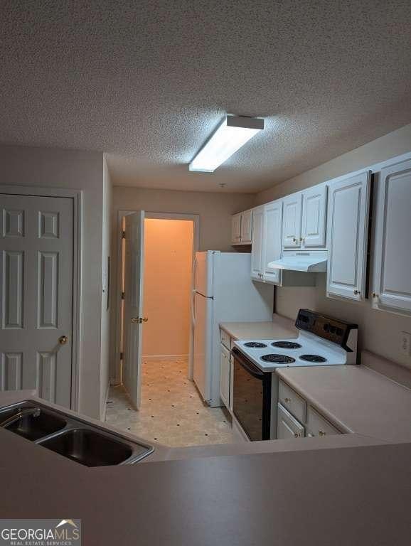 kitchen with white cabinets, a textured ceiling, white appliances, and sink