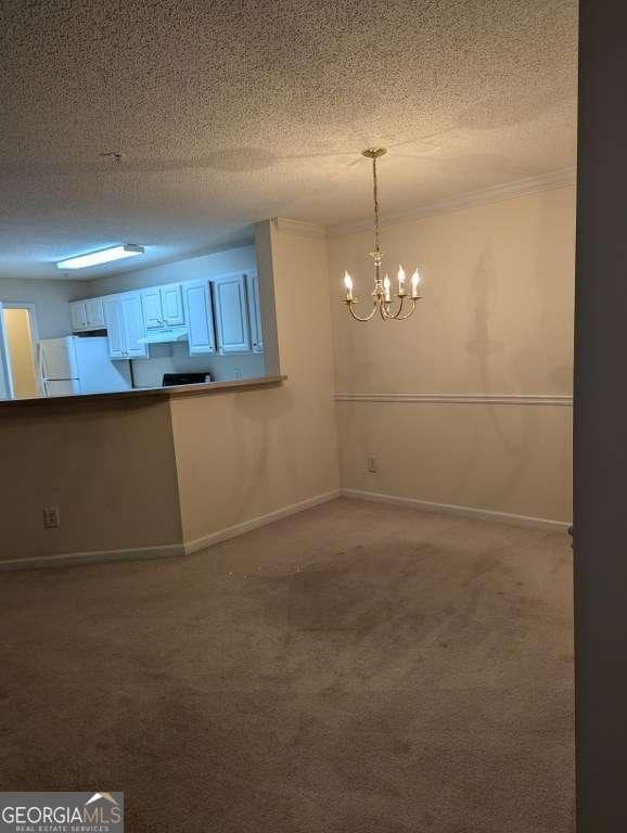 spare room with carpet flooring, a textured ceiling, and an inviting chandelier