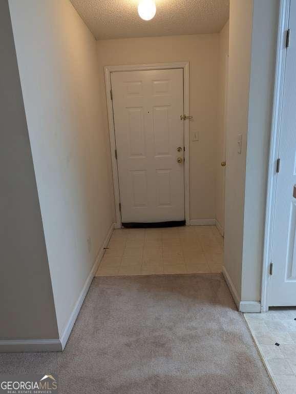 entryway with light colored carpet and a textured ceiling