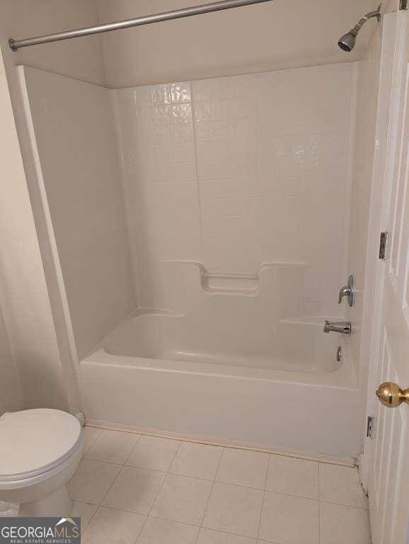 bathroom with tile patterned floors, toilet, and shower / washtub combination