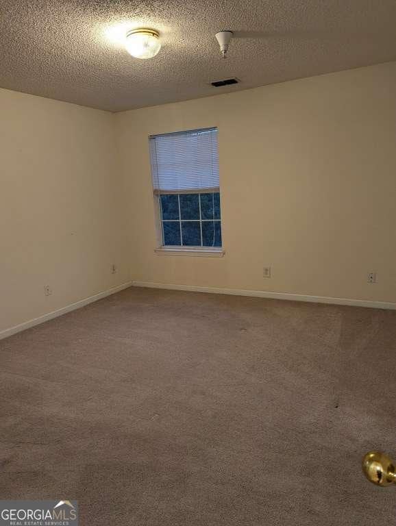 empty room with a textured ceiling and carpet floors