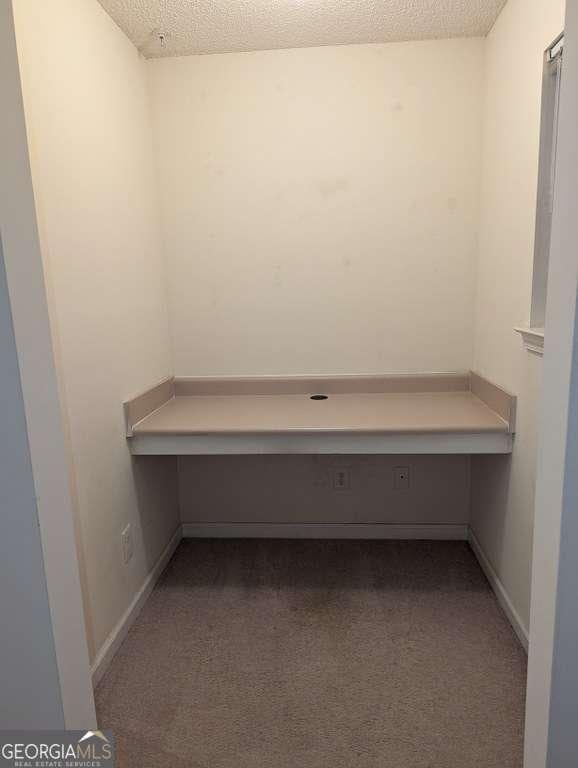 unfurnished office featuring light colored carpet and a textured ceiling