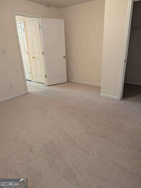 unfurnished bedroom with a walk in closet, light carpet, and a closet