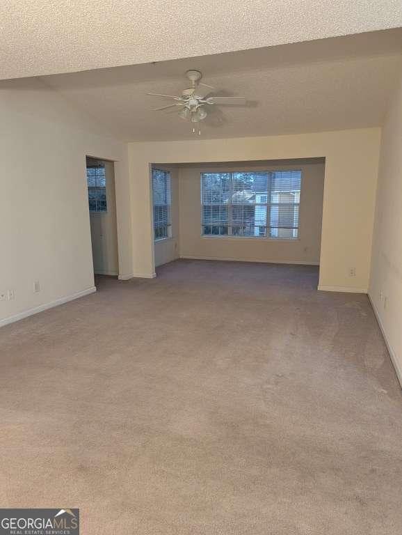 spare room with ceiling fan, light carpet, and a textured ceiling