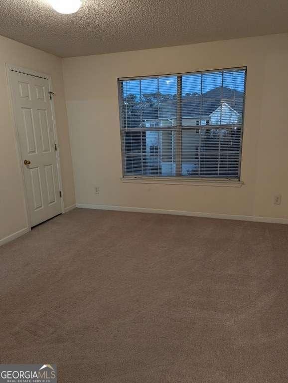 empty room with a textured ceiling and carpet floors