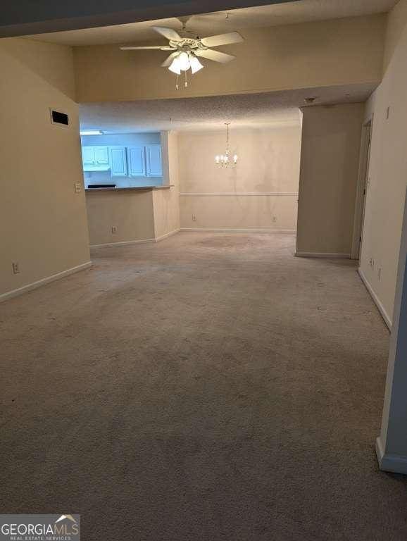 interior space featuring carpet and ceiling fan with notable chandelier