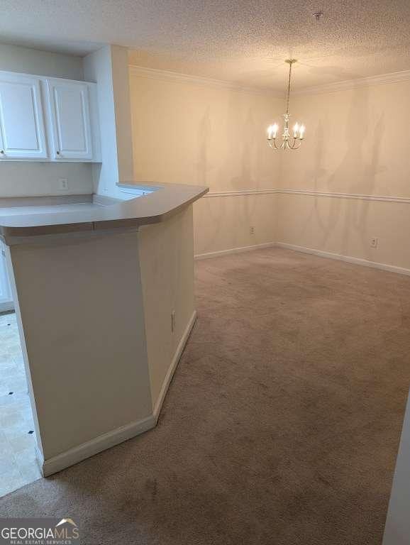 kitchen featuring white cabinets, pendant lighting, a textured ceiling, and light carpet