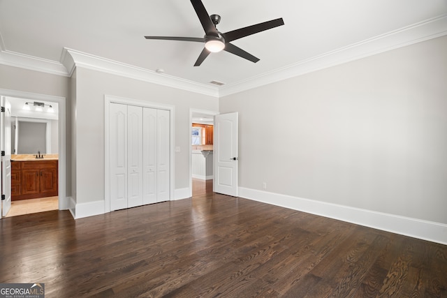 unfurnished bedroom featuring sink, crown molding, ensuite bath, ceiling fan, and a closet