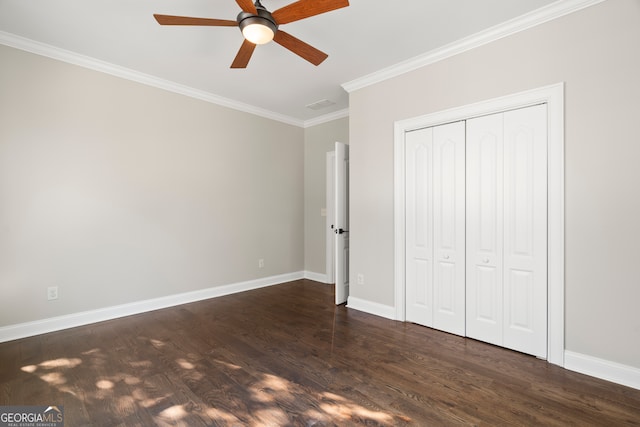 unfurnished bedroom with ceiling fan, dark wood-type flooring, crown molding, and a closet