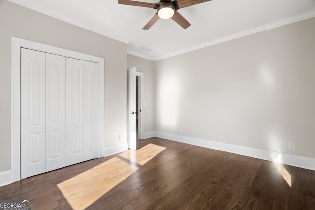 unfurnished bedroom with ceiling fan, a closet, dark hardwood / wood-style floors, and ornamental molding