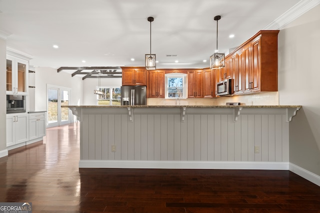 kitchen featuring hanging light fixtures, appliances with stainless steel finishes, dark hardwood / wood-style flooring, kitchen peninsula, and a breakfast bar area