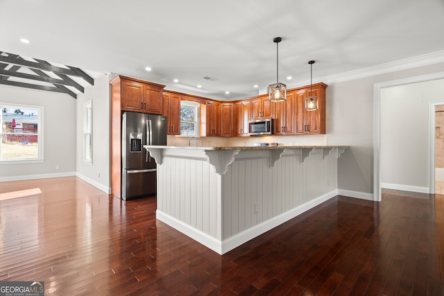 kitchen with pendant lighting, a kitchen bar, kitchen peninsula, and stainless steel appliances