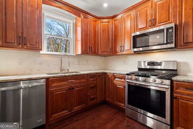 kitchen featuring dark wood-type flooring, sink, decorative backsplash, light stone countertops, and appliances with stainless steel finishes