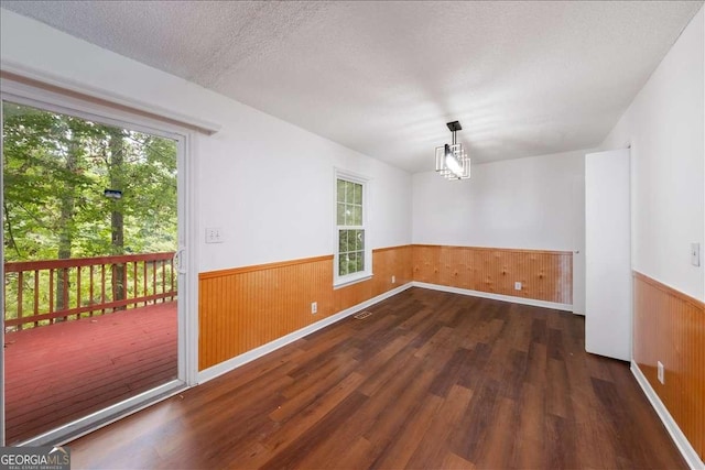 unfurnished room with dark wood-type flooring, a chandelier, and a textured ceiling