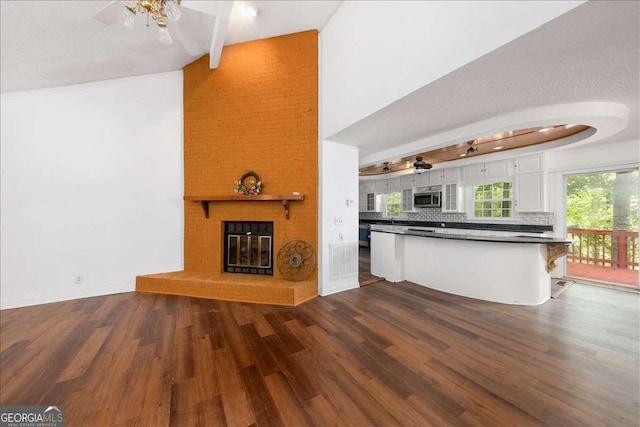 kitchen with a breakfast bar, backsplash, a fireplace, white cabinets, and dark hardwood / wood-style flooring