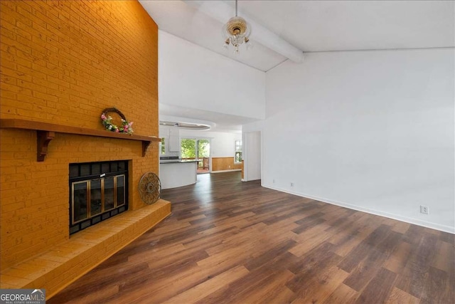 unfurnished living room with a brick fireplace, vaulted ceiling with beams, and dark wood-type flooring