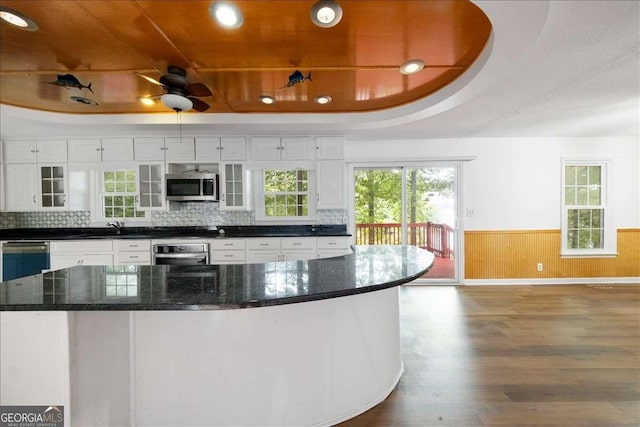 kitchen featuring a raised ceiling, appliances with stainless steel finishes, hardwood / wood-style floors, and white cabinets