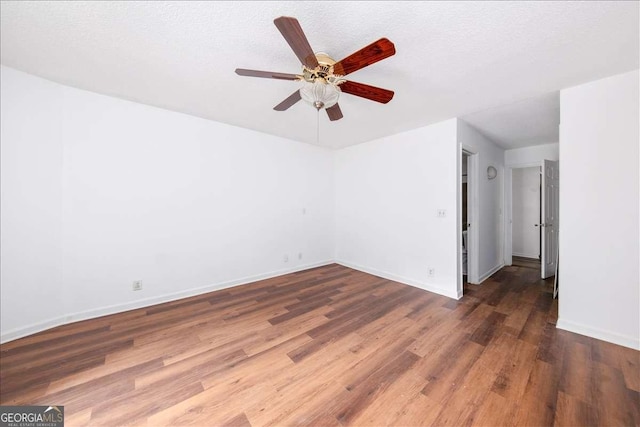 spare room with ceiling fan, a textured ceiling, and dark hardwood / wood-style flooring