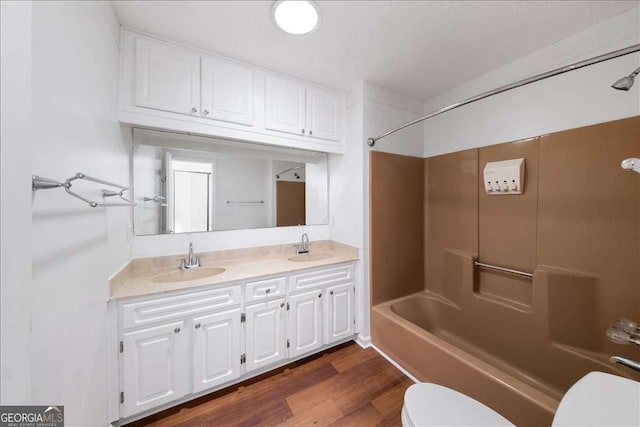 full bathroom with hardwood / wood-style flooring, vanity, shower / tub combination, and toilet