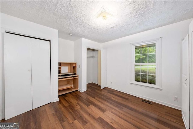 unfurnished bedroom with a textured ceiling and dark hardwood / wood-style flooring