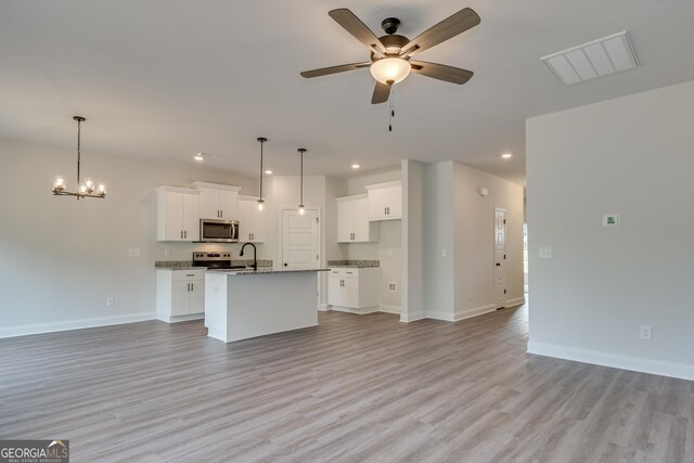 unfurnished living room with ceiling fan with notable chandelier and light hardwood / wood-style floors