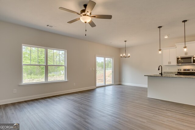 unfurnished living room featuring dark hardwood / wood-style flooring, ceiling fan with notable chandelier, and sink