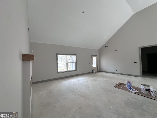 unfurnished living room featuring high vaulted ceiling and baseboards