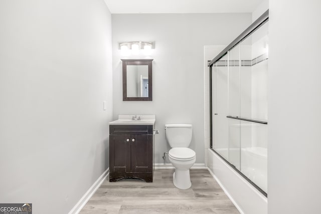 full bathroom featuring vanity, hardwood / wood-style floors, toilet, and combined bath / shower with glass door