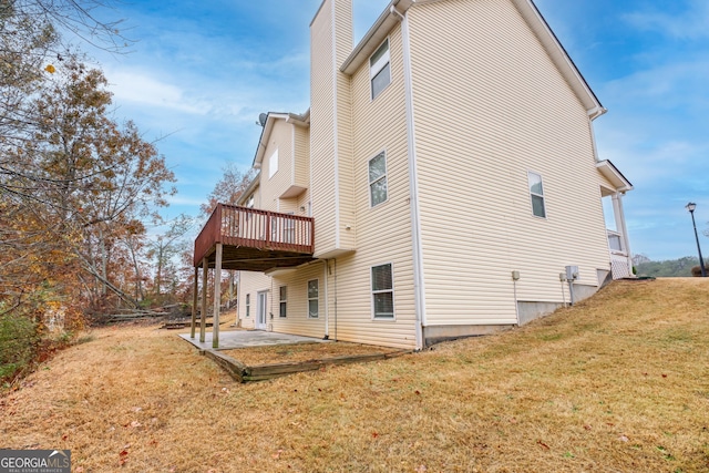 rear view of property featuring a patio, a deck, and a lawn