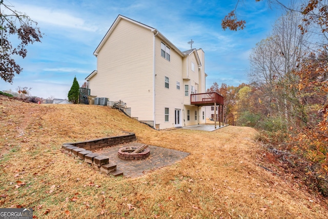 rear view of property with a wooden deck, a fire pit, a patio, and a yard