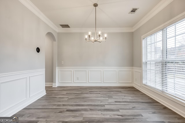 unfurnished dining area featuring ornamental molding, hardwood / wood-style floors, and a chandelier