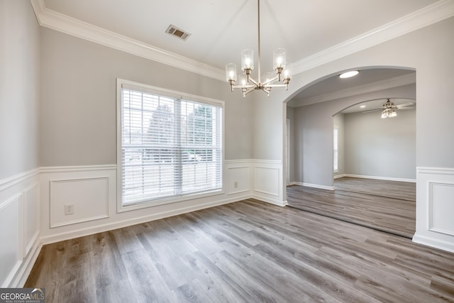 unfurnished dining area featuring hardwood / wood-style flooring, ornamental molding, and ceiling fan with notable chandelier