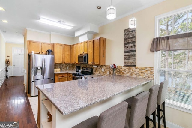 kitchen with a breakfast bar, tasteful backsplash, decorative light fixtures, kitchen peninsula, and stainless steel appliances